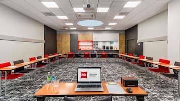 Une salle de conférence équipée de plusieurs tables, de chaises, d’un ordinateur portable et d’un projecteur.