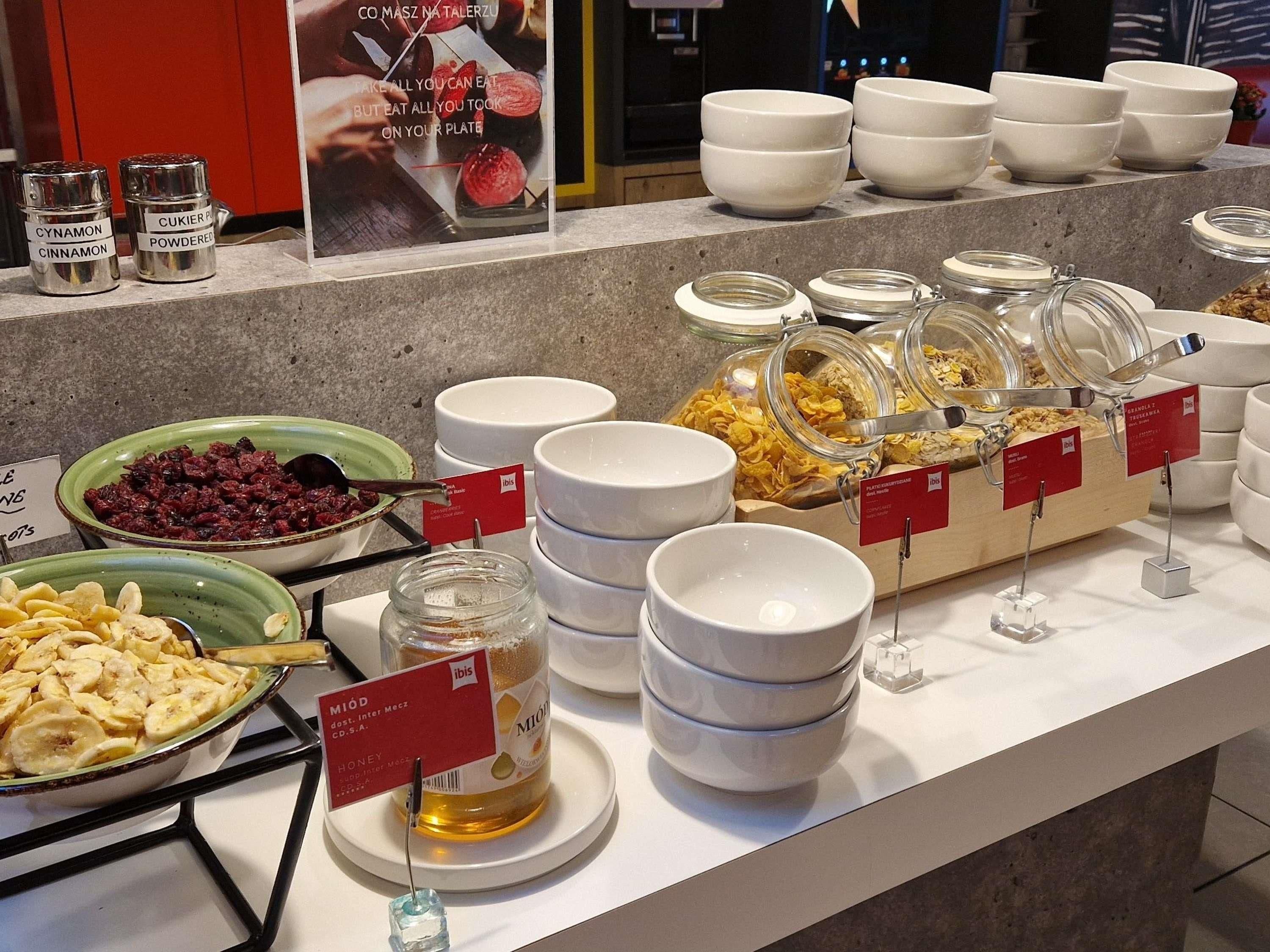 Un buffet proposant une variété d’aliments, notamment des bols de céréales, un pot de miel et des boîtes d’épices.