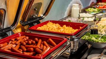 A buffet with various food items including sausages, macaroni, and salads.