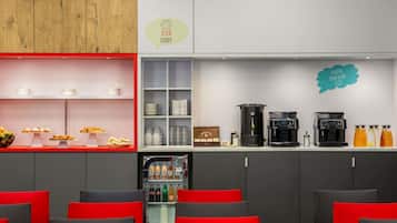 Zona de bar moderna con una máquina de café, dispensadores de bebidas y una presentación de aperitivos.