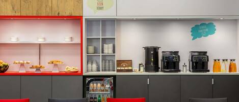 Zona de bar moderna con una máquina de café, dispensadores de bebidas y una presentación de aperitivos.