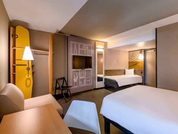 Een hotelkamer met een bed, een bureau, een stoel, een televisie en een kledingkast.