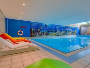 Une piscine intérieure avec un mur recouvert de carreaux bleus et une bouée de sauvetage.