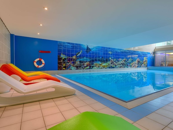 An indoor swimming pool with a blue tiled wall and a lifebuoy.