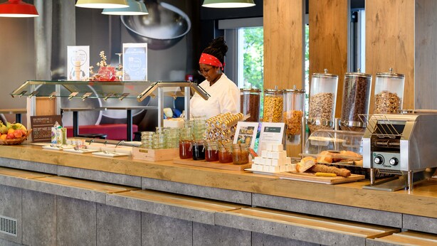 Un bar pour le petit-déjeuner avec divers aliments, une machine à café et des lampes suspendues.