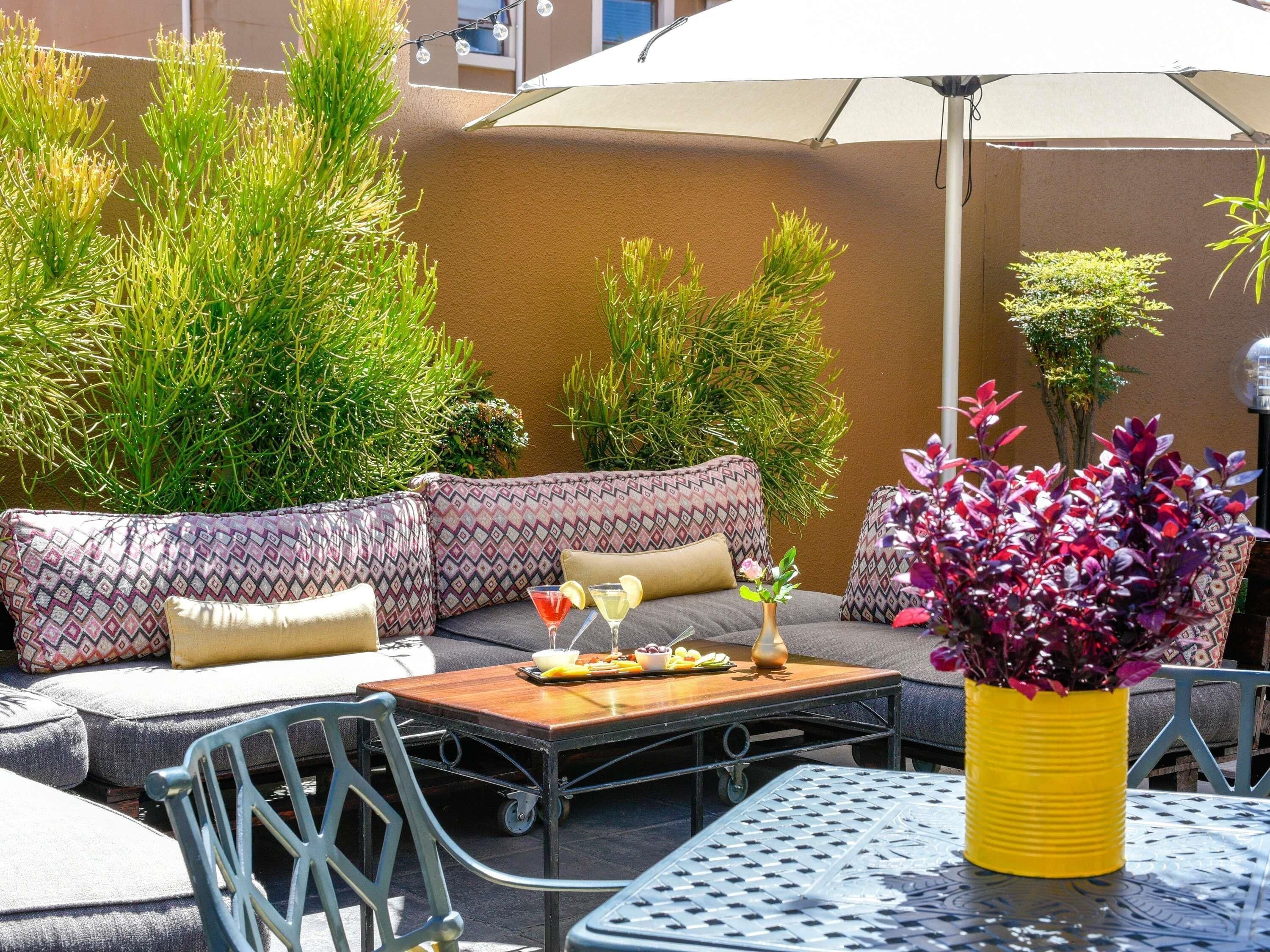 An outdoor seating area with a sofa, chairs, a table, and a potted plant.