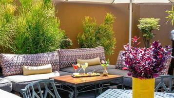 An outdoor seating area with a sofa, chairs, a table, and a potted plant.