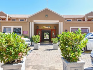 A hotel entrance with a tiled roof, a signboard, and potted plants. - Mercure Johannesburg Bedfordview Hotel (Germiston)