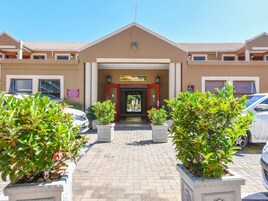 A hotel entrance with a tiled roof, a signboard, and potted plants.