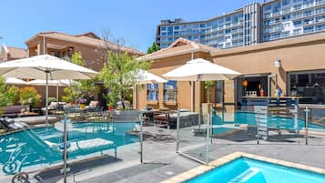 Alberca al aire libre, sombrillas en la alberca y camastros