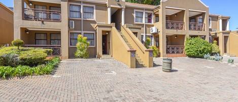 A multi-story residential building with a brick courtyard, balconies, and a central staircase.