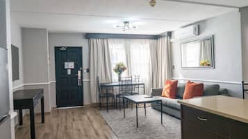 A compact living space with a kitchenette, a dining area, and a seating area with a sofa and a coffee table.