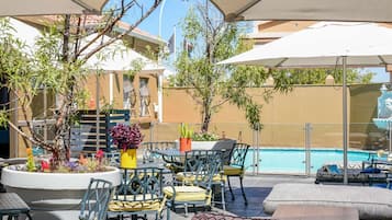 Una piscina al aire libre, sombrillas, sillones reclinables de piscina