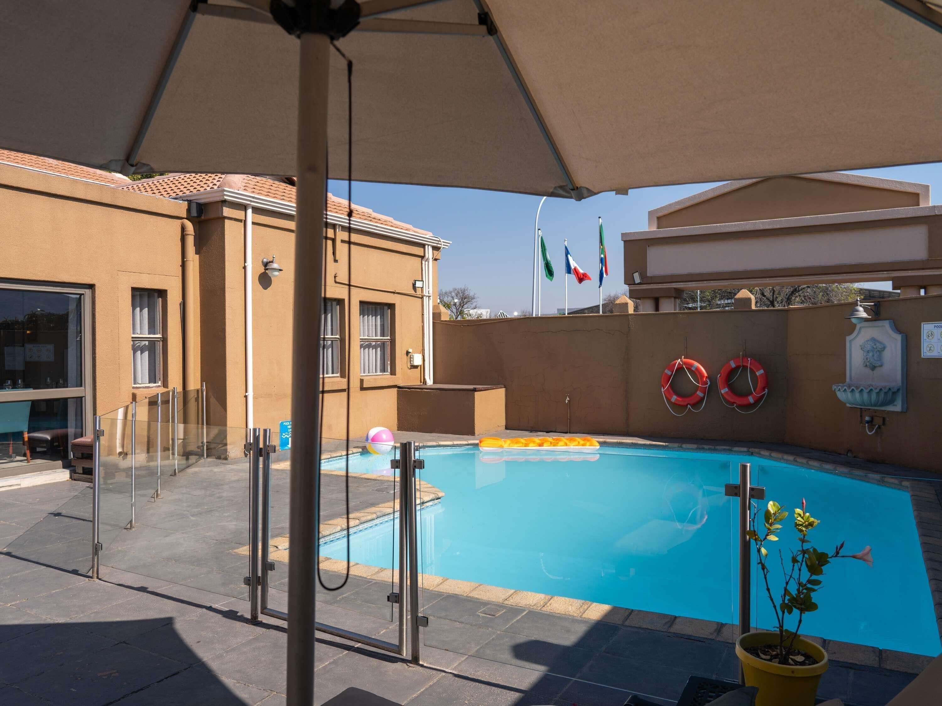 A swimming pool with a glass enclosure, a lifebuoy, and a flag.