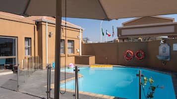 Una piscina con cerramiento de vidrio, un flotador salvavidas y una bandera.