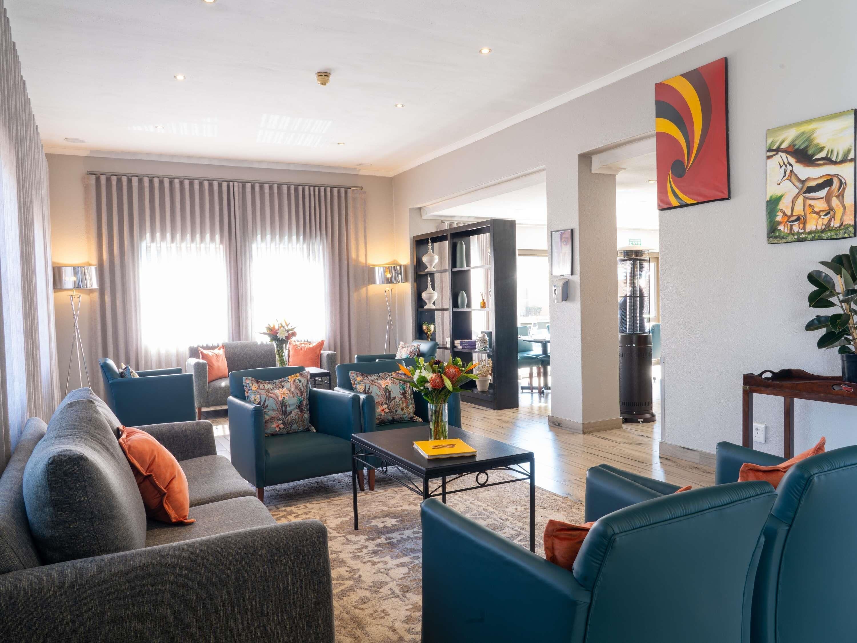 A modern living room with a sofa, armchairs, a coffee table, and a bookshelf.