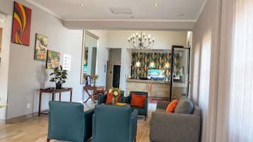 Una sala de estar moderna con un sofá, sillas, una mesa de centro y un televisor.