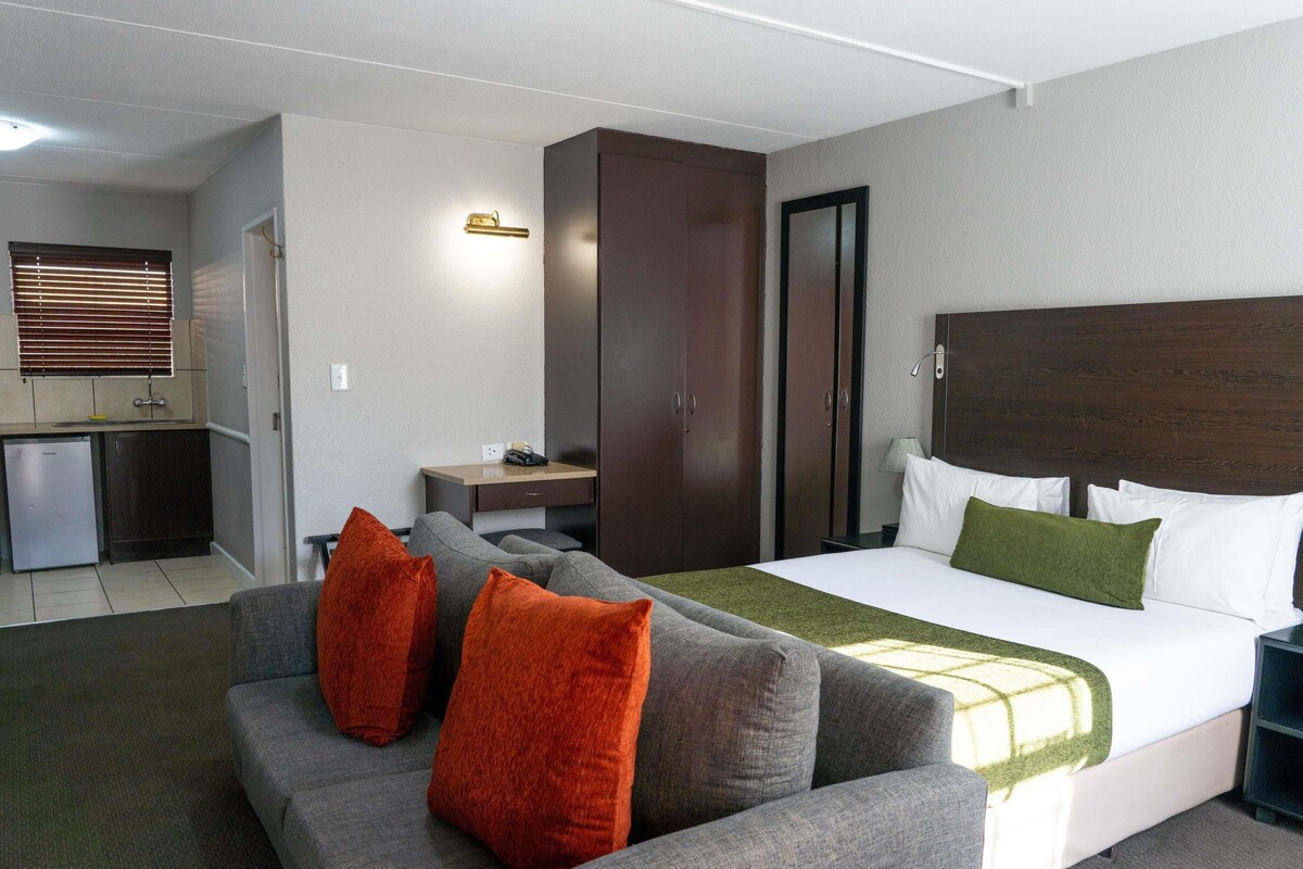 A hotel room with a bed, a sofa, a desk, and a wardrobe.