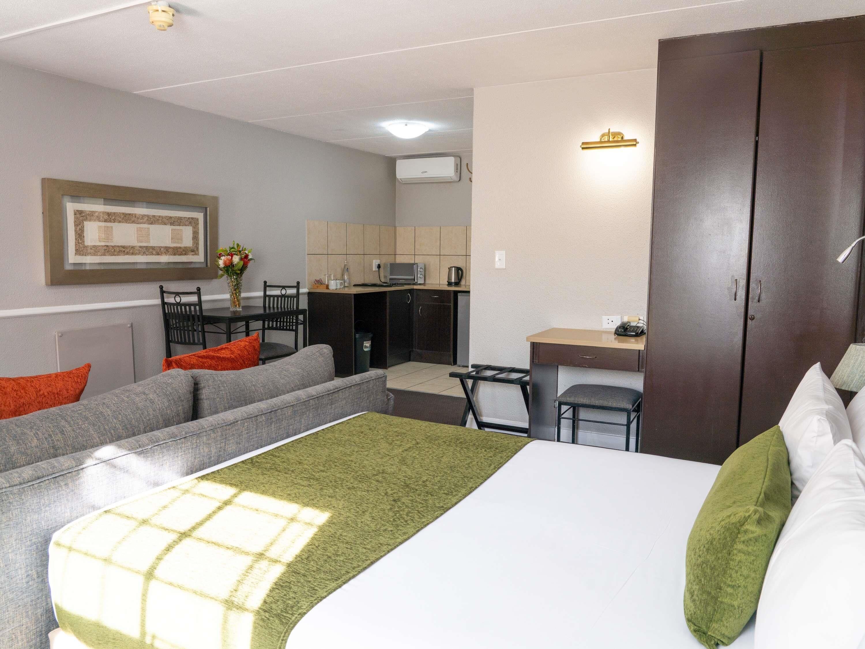 Una habitación de hotel con una cama, un sofá, un escritorio y una kitchenette.