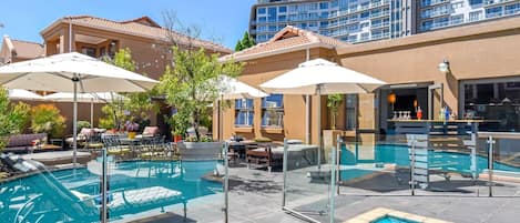 Una piscina al aire libre, sombrillas, sillones reclinables de piscina