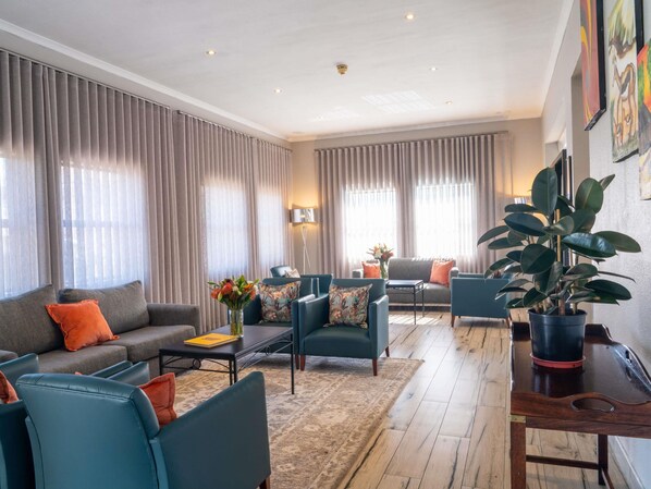A modern living room with a sofa, armchairs, a coffee table, and a potted plant.