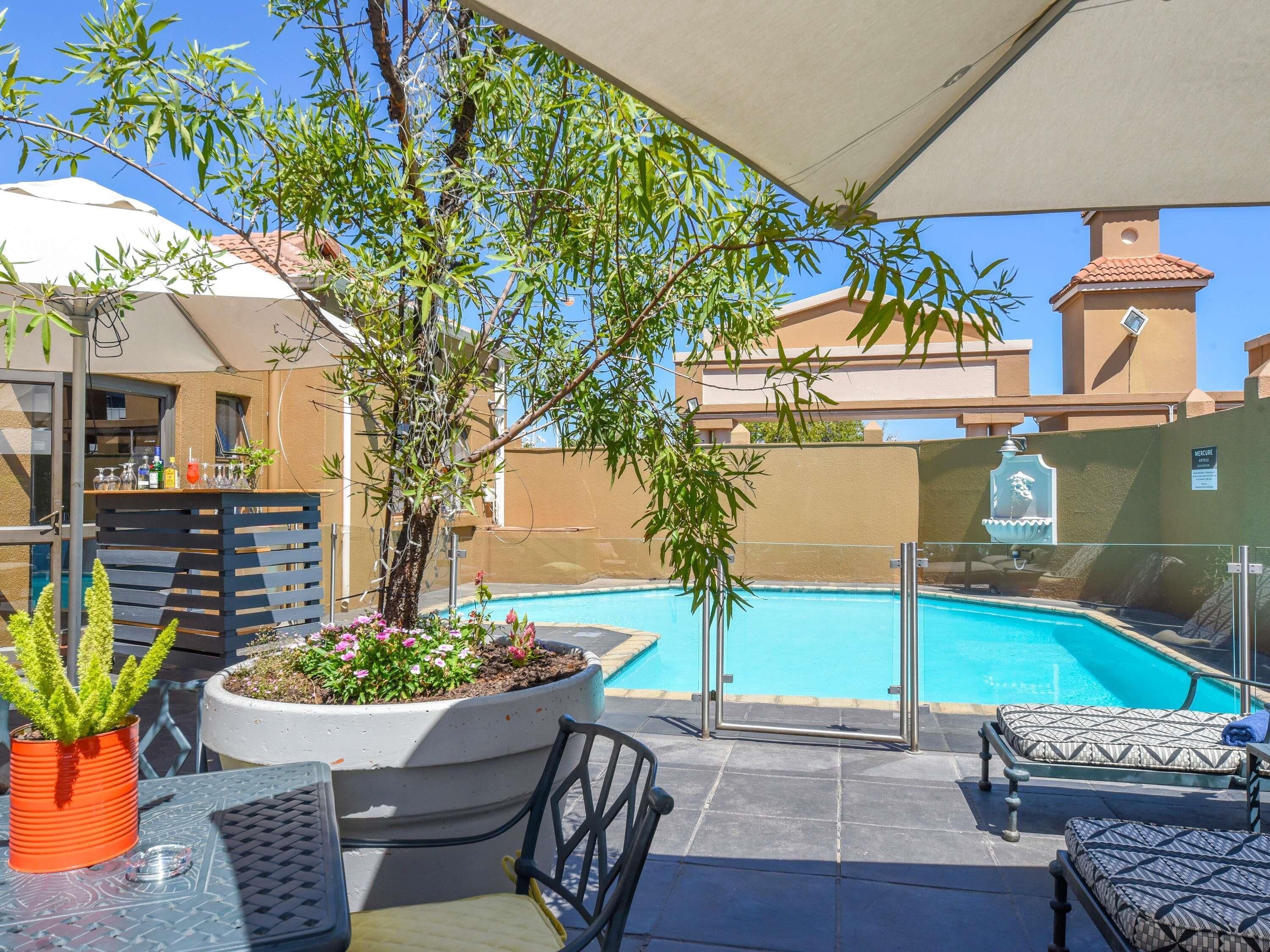 Una piscina al aire libre, sombrillas, sillones reclinables de piscina