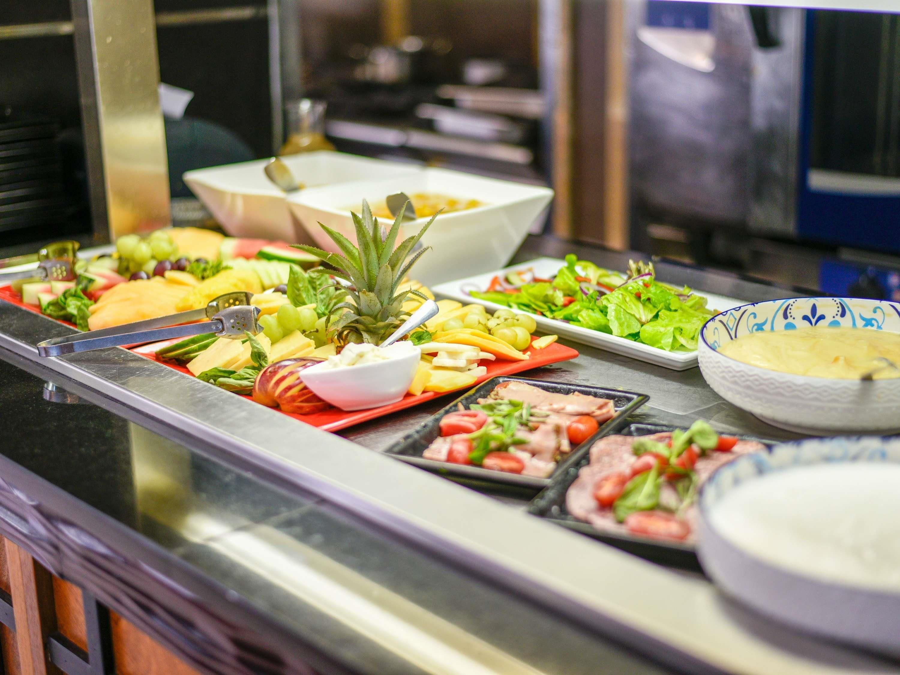A buffet with various food items including fruits, vegetables, and meats.