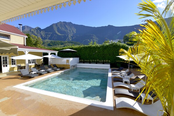 Una piscina al aire libre, sillones reclinables de piscina