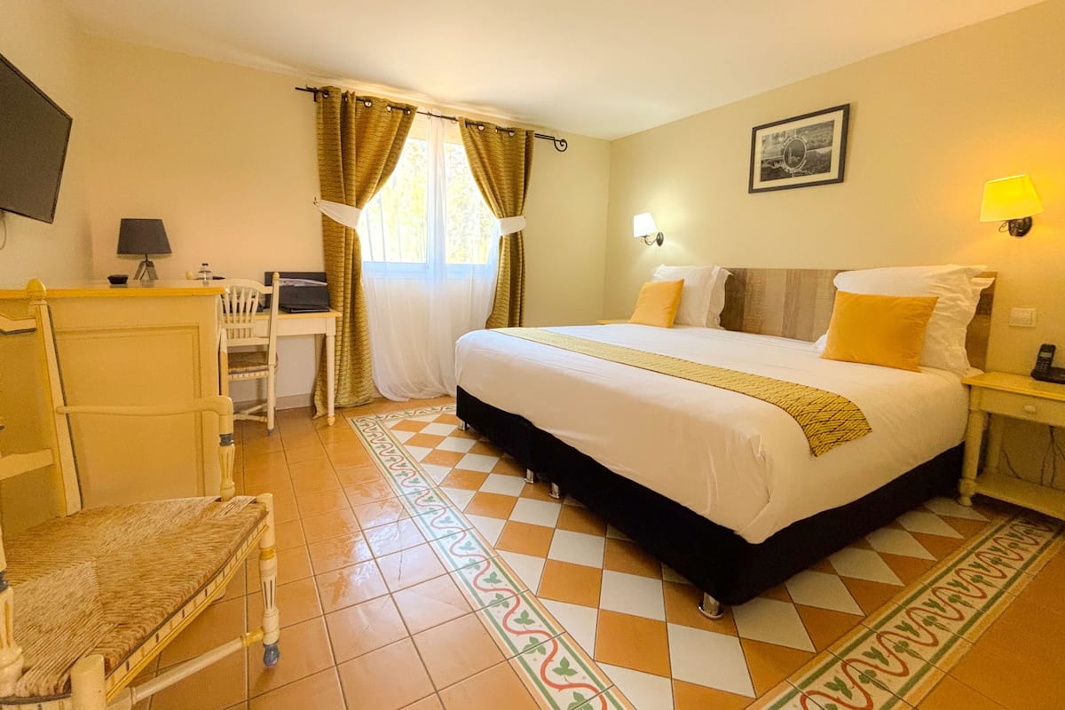Een hotelkamer met een bed, bureau, stoel en een raam met gordijnen.