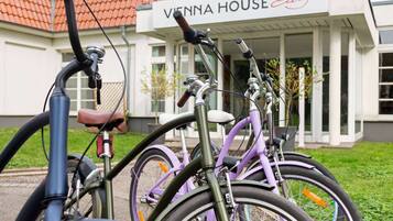 Una fila di biciclette parcheggiate di fronte a un edificio con un cartello che riporta la scritta 'VENNA HOUSE Easy'.