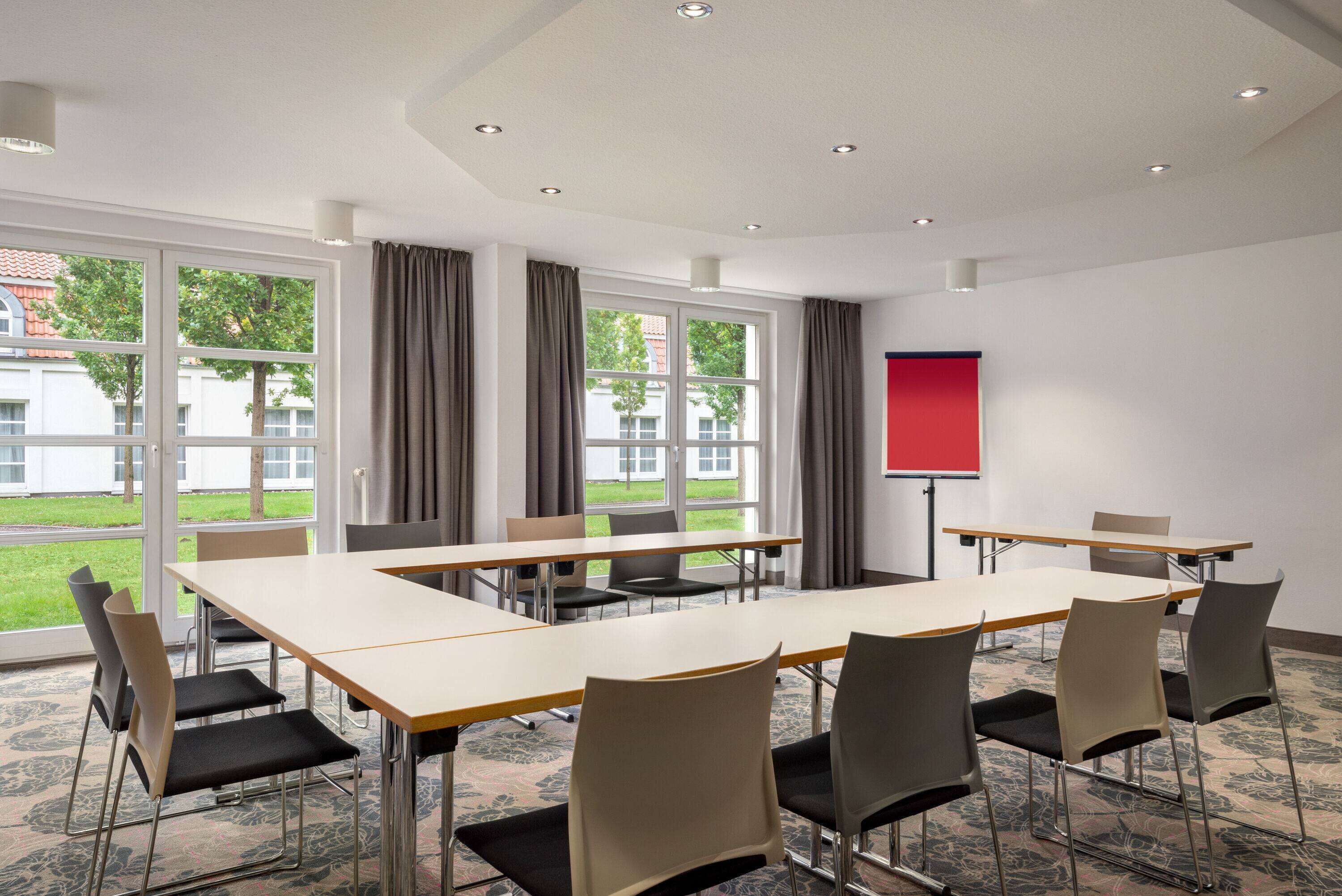A conference room with a long table, chairs, and a projector screen.