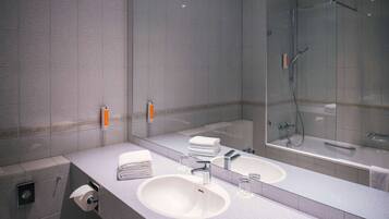 Une salle de bain moderne avec deux lavabos, un grand miroir et une douche à parois de verre.