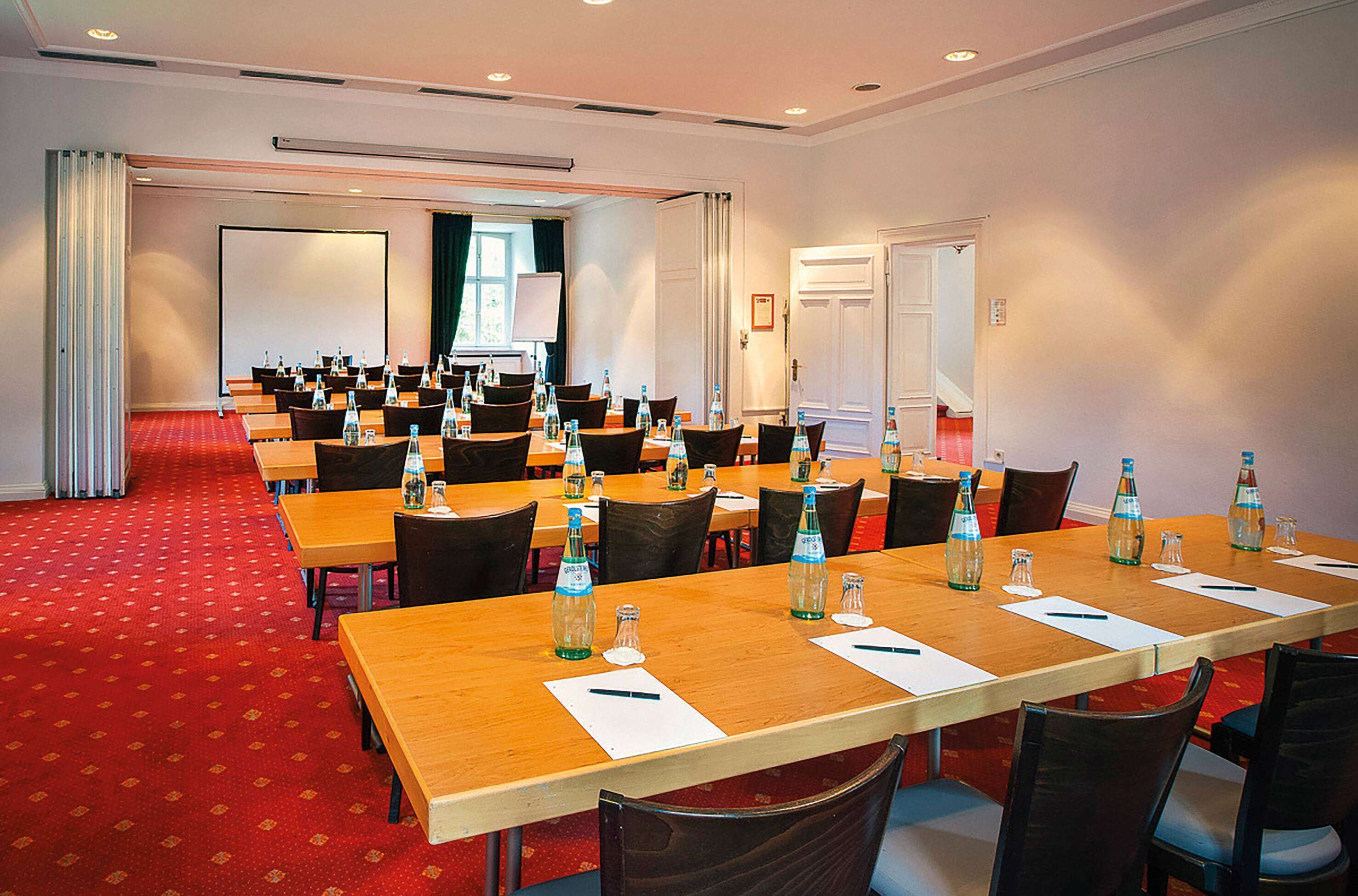 A conference room with multiple tables, chairs, and water bottles.