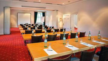 A conference room with multiple tables, chairs, and water bottles.