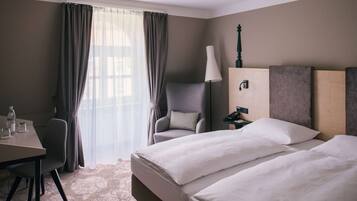 A hotel room with two beds, a desk, a chair, a lamp, and a nightstand.