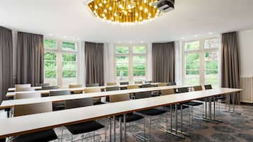 A conference room with long tables, chairs, and large windows with curtains.