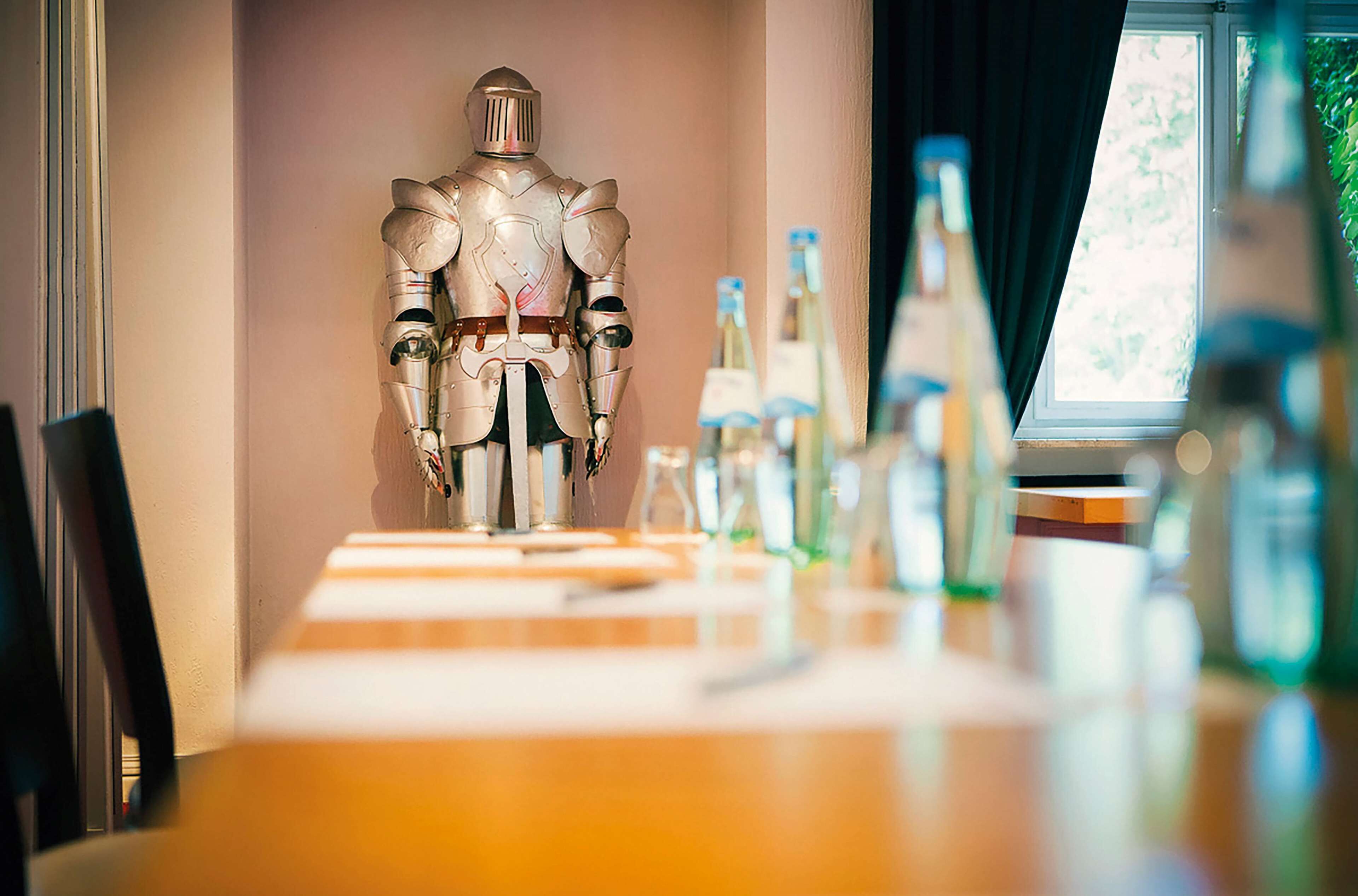 Ein Zimmer mit einem für das Essen gedeckten Tisch, einer Roboterfigur und Weinflaschen.