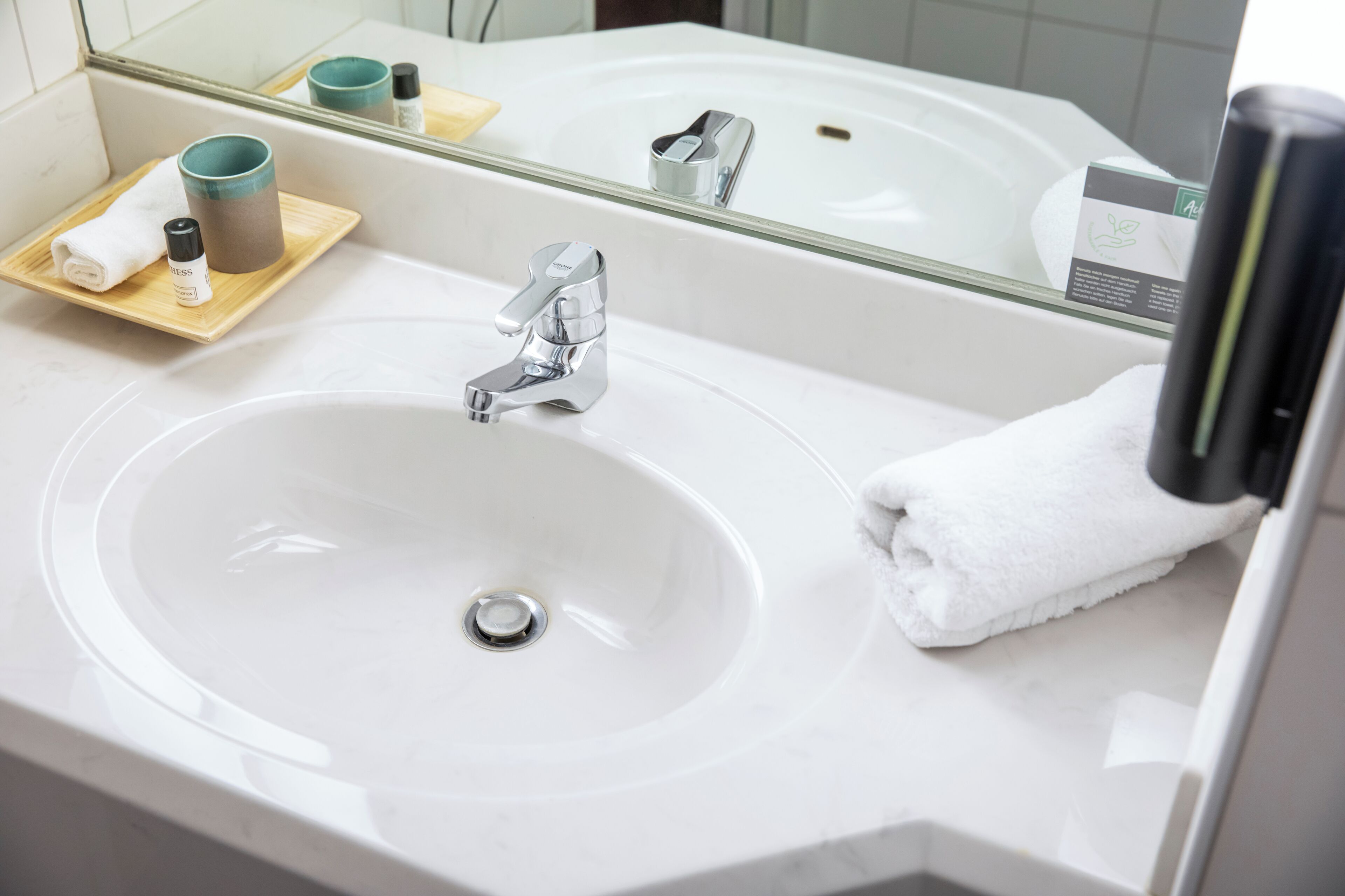 Ein Badezimmer mit einem weißen Waschbecken, einem Spiegel und einem Handtuch auf der Ablagefläche.