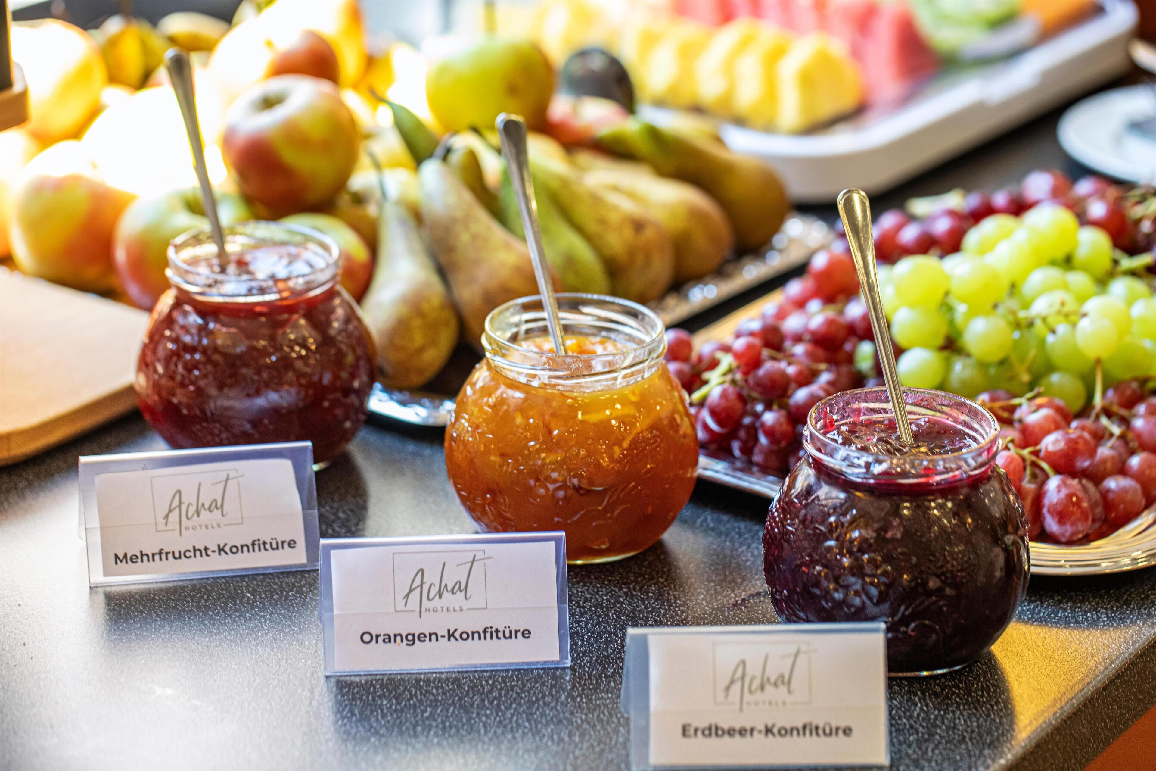 Une table de buffet garnie de divers fruits et de pots de confitures.