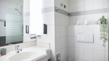 A modern bathroom with a white sink, a mirror, a shower, and a towel rack.