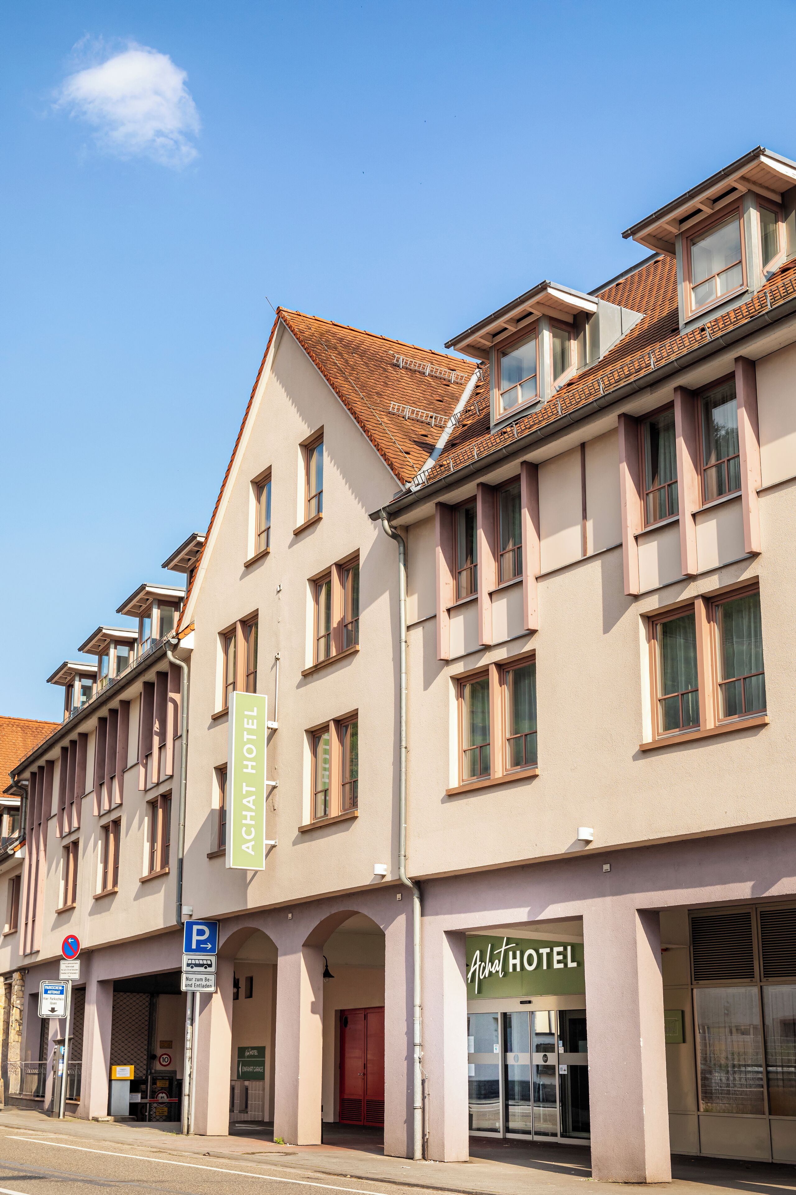 A hotel with a classic European architectural style, featuring a prominent entrance with a red door, multiple windows, and a green signboard.