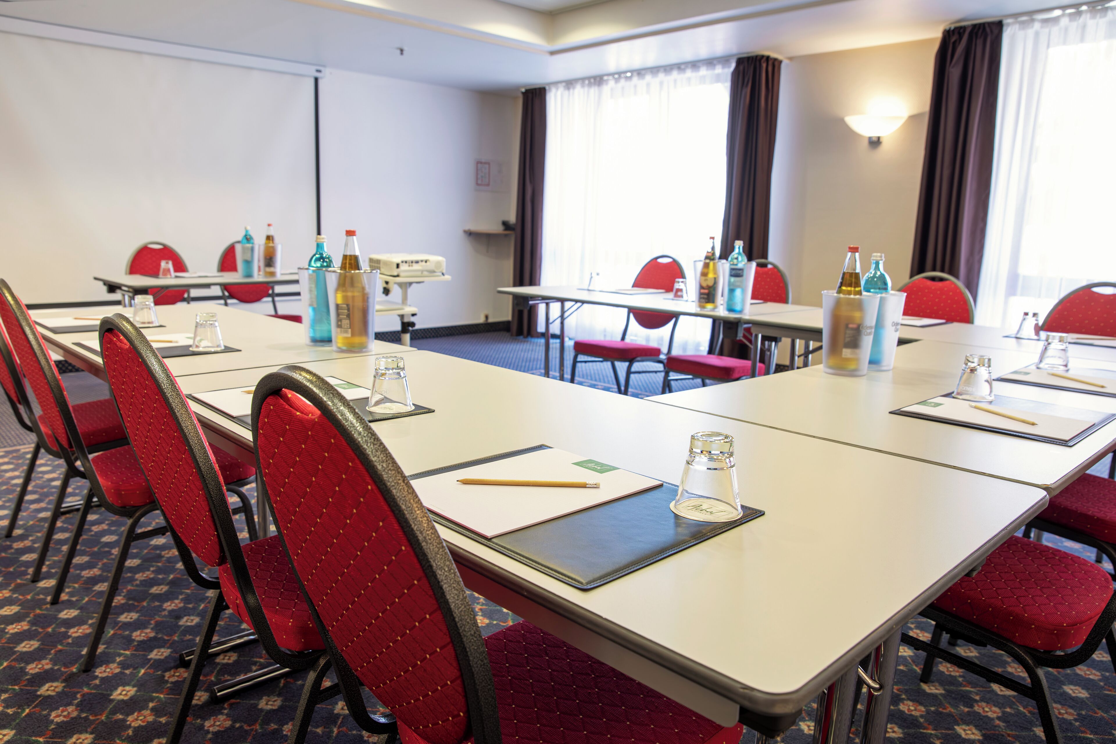 Un salón de conferencias con mesas, sillas y varios servicios como botellas y vasos.