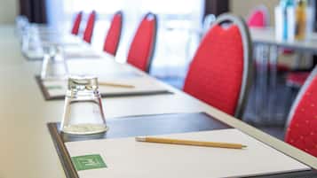 A conference room with a long table, red chairs, and a water bottle on each seat.
