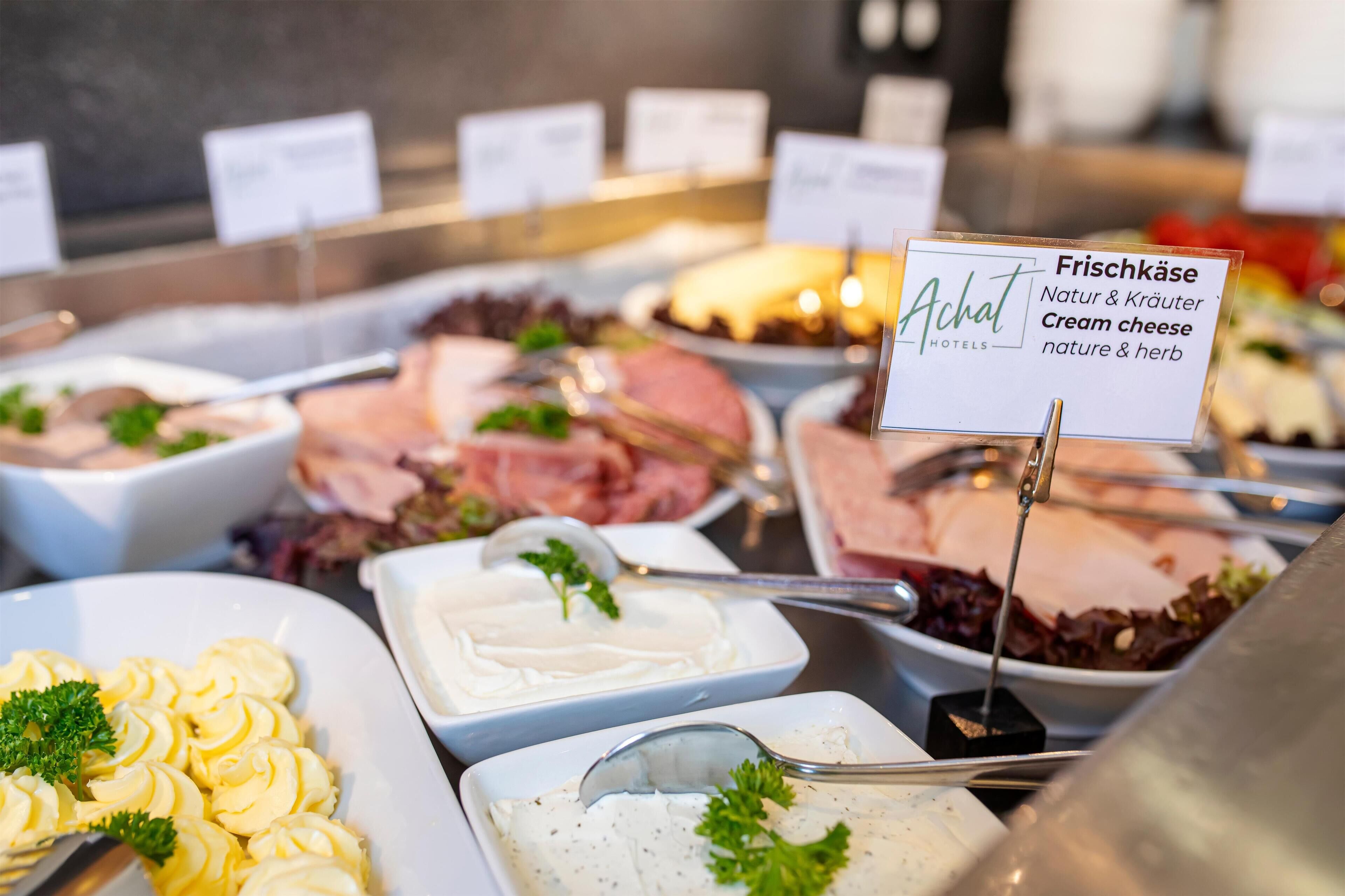 A buffet with various food options including cream cheese, salads, and meats.