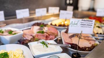 A buffet with various food options including cream cheese, salads, and meats.