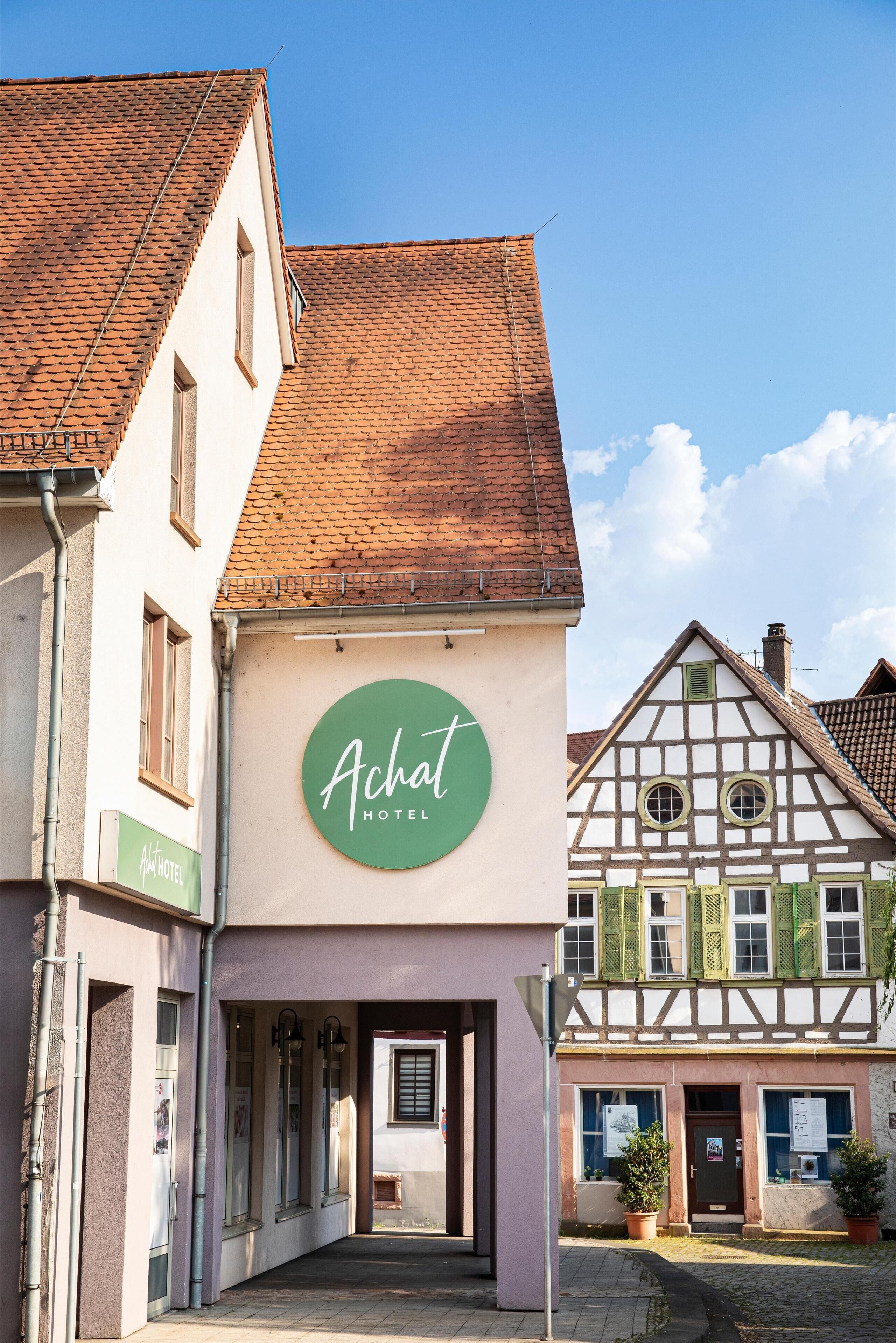 A traditional European building with a sign for 'Achat Hotel'.
