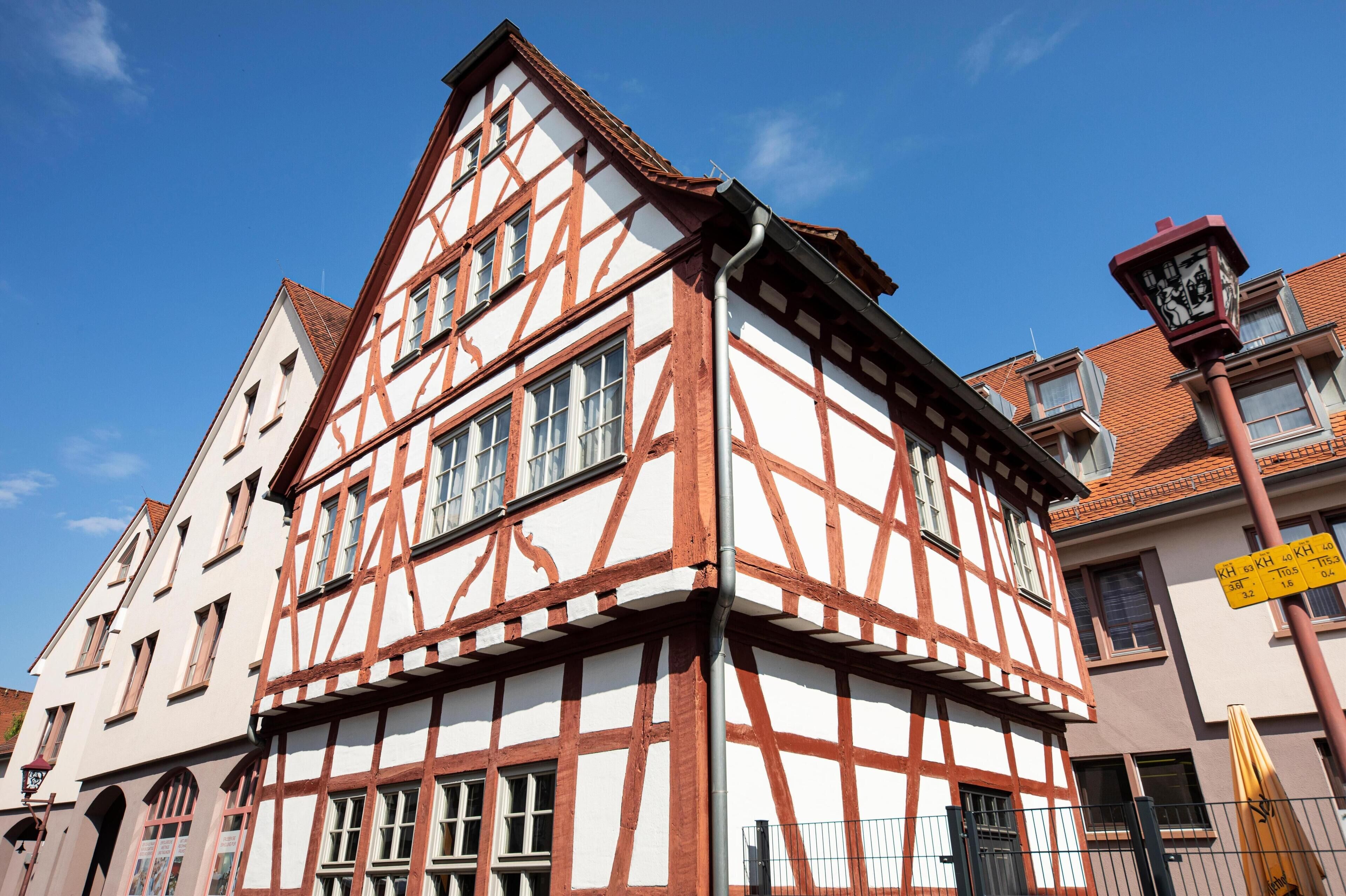 Un bâtiment traditionnel à colombages, doté de nombreuses fenêtres et d’une enseigne visible donnant sur la rue.