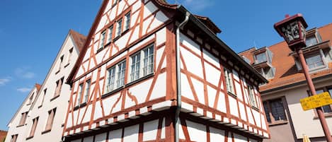 Un edificio tradicional de entramado de madera con múltiples ventanas y una señal de calle visible.