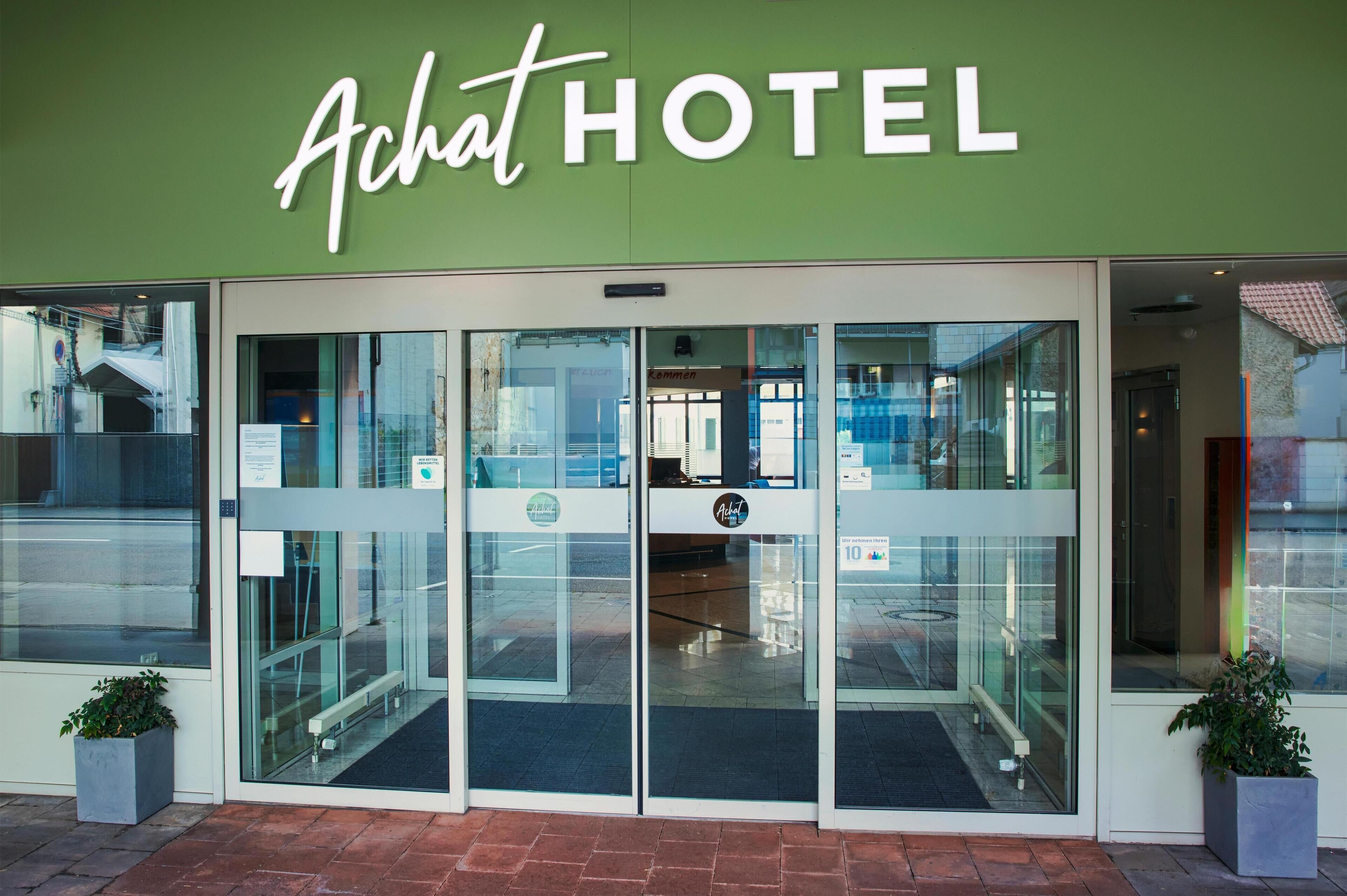 The exterior of a hotel with a green facade and a glass entrance.