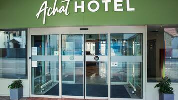 The exterior of a hotel with a green facade and a glass entrance.